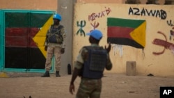 FILE - United Nations peacekeepers stand guard at the entrance to a polling station covered in separatist flags and graffiti supporting the creation of the independent state of Azawad, in Kidal, Mali, on July 27, 2013.
